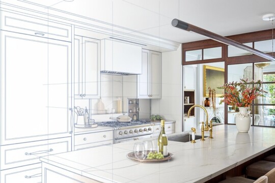 White marble island, gold faucet, wine and glass on a tray, vase of flowers; left side shows blueprint lines over cabinets in a kitchen.